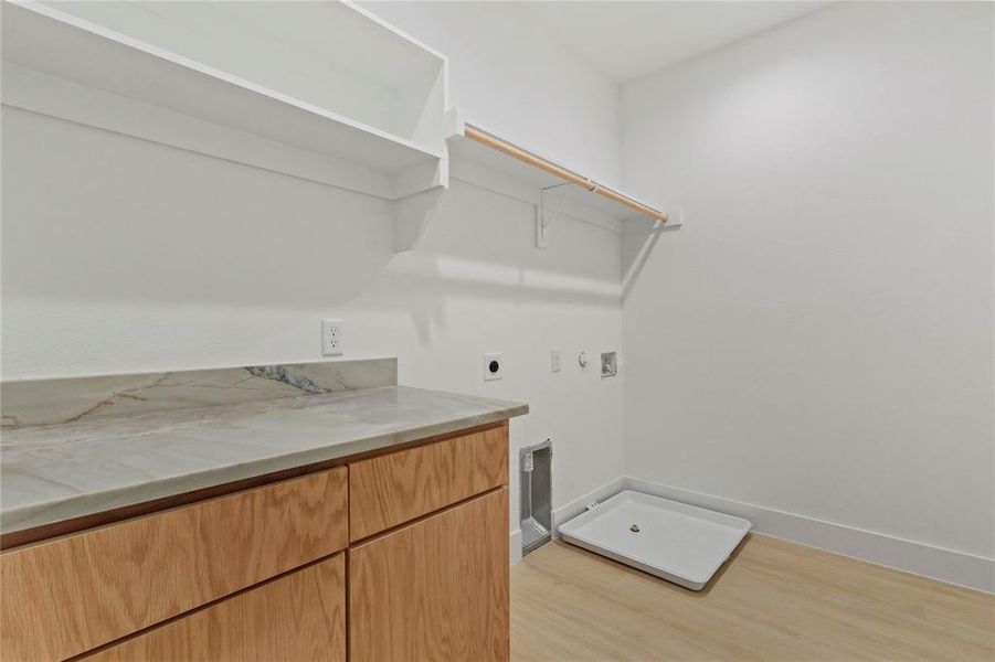 Washroom with hookup for an electric dryer, light wood-style flooring, and hookup for a gas dryer Washroom with hookup for an electric dryer, light wood-style flooring, and hookup for a gas dryer