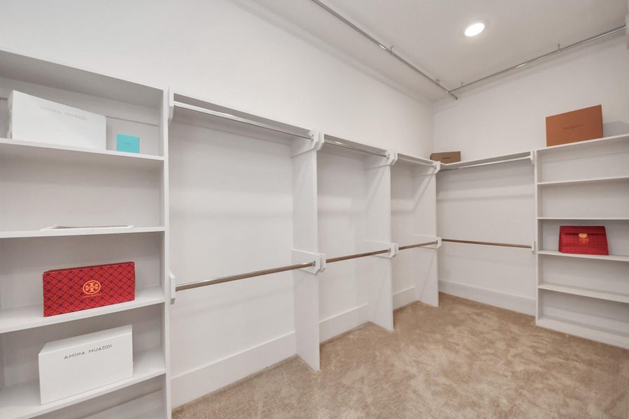 Oversized primary walk-in closet offers sleek organization systems and a dressing area. Oversized primary walk-in closet offers sleek organization systems and a dressing area.