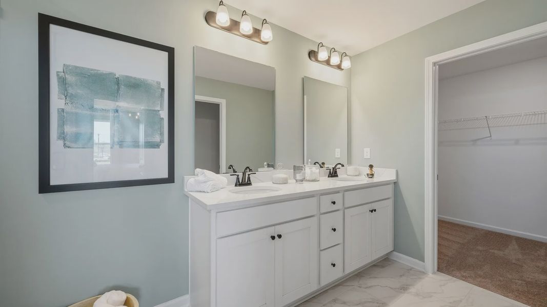Modern primary bathroom with double vanity and convenient walk-in closet in Langley Overlook townhome in Loganville, GA Modern primary bathroom with double vanity and convenient walk-in closet in Langley Overlook townhome in Loganville, GA