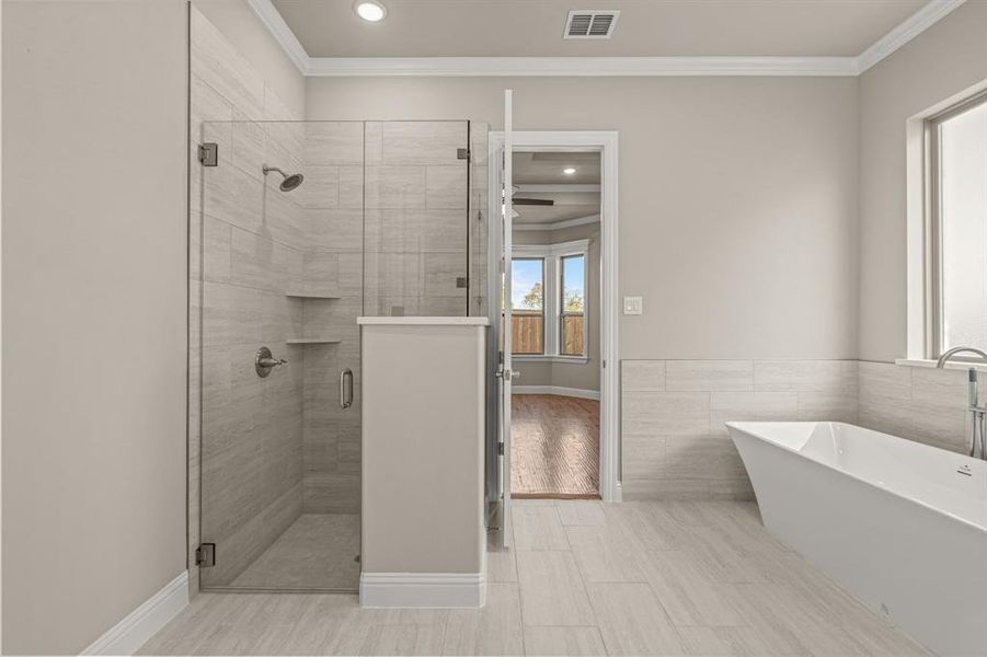 Bathroom featuring a soaking tub, a shower stall, recessed lighting, ornamental molding, and tile walls Bathroom featuring a soaking tub, a shower stall, recessed lighting, ornamental molding, and tile walls
