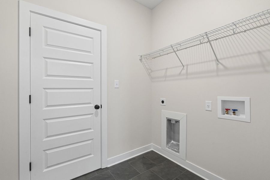 Laundry room featuring electric dryer hookup, hookup for a washing machine, and dark tile patterned flooring Laundry room featuring electric dryer hookup, hookup for a washing machine, and dark tile patterned flooring