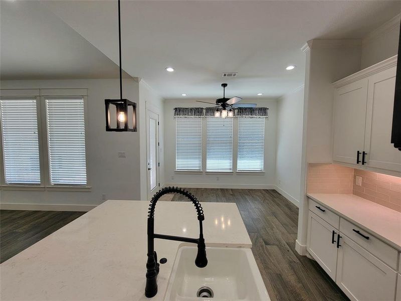 Kitchen with white cabinetry, sink, ceiling fan, pendant lighting, and decorative backsplash