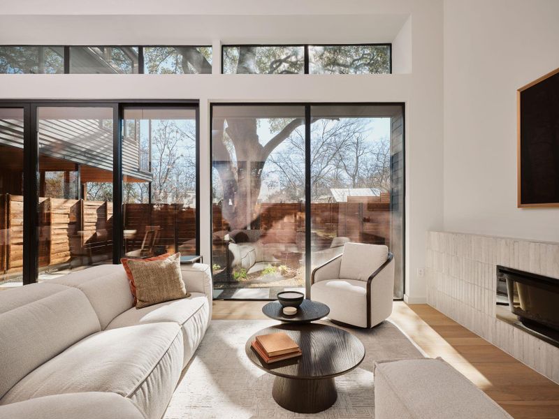 Living room with wood finished floors, a fireplace, and a high ceiling