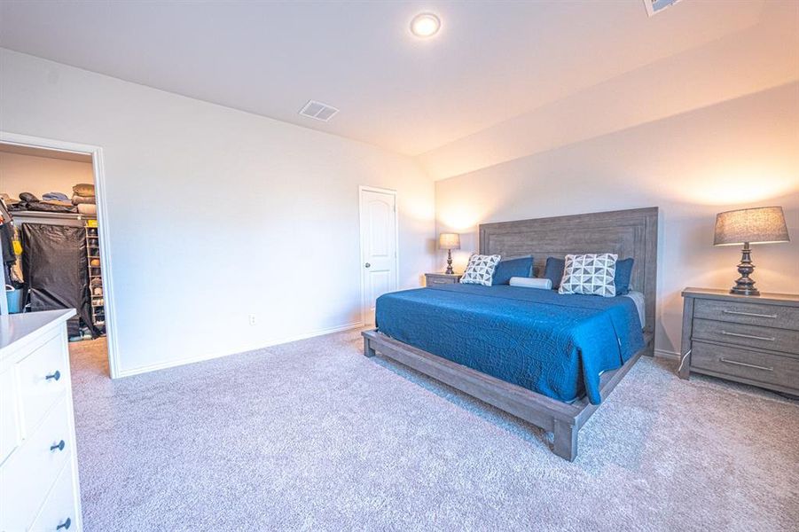Bedroom with light colored carpet and a walk in closet