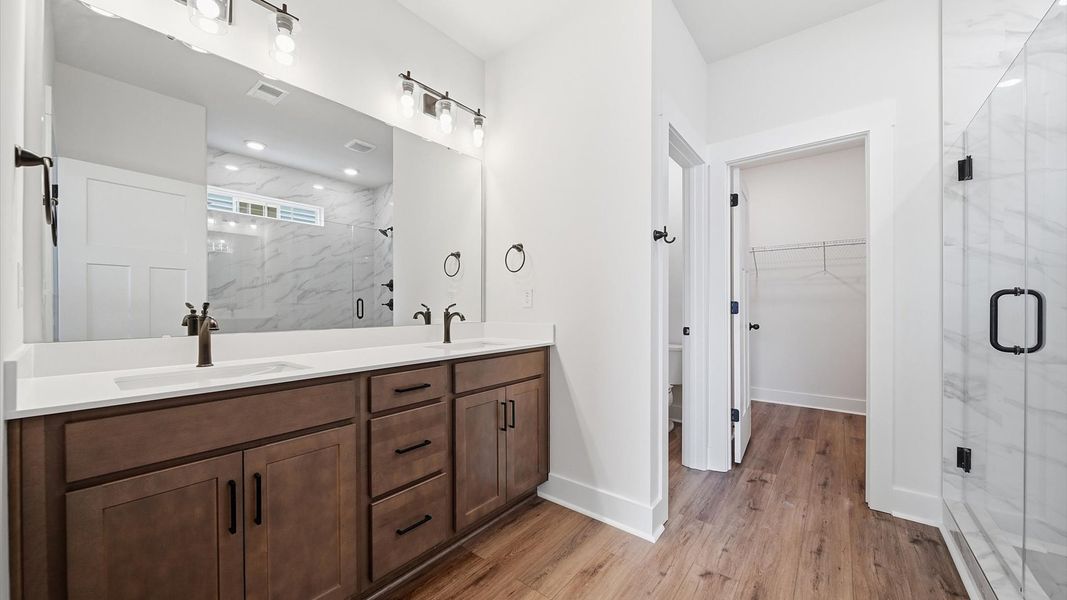 Accomplished design shines in this primary bath with dual vanity and a sleek walk-in shower