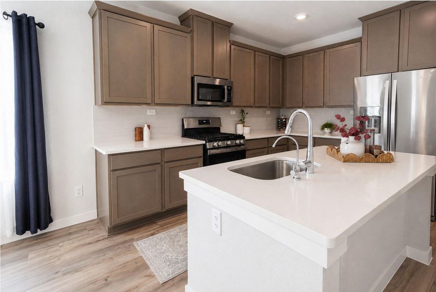 Gleaming stone countertops and matching cabinetry surround a central prep island with dual-basin sink. Gleaming stone countertops and matching cabinetry surround a central prep island with dual-basin sink.