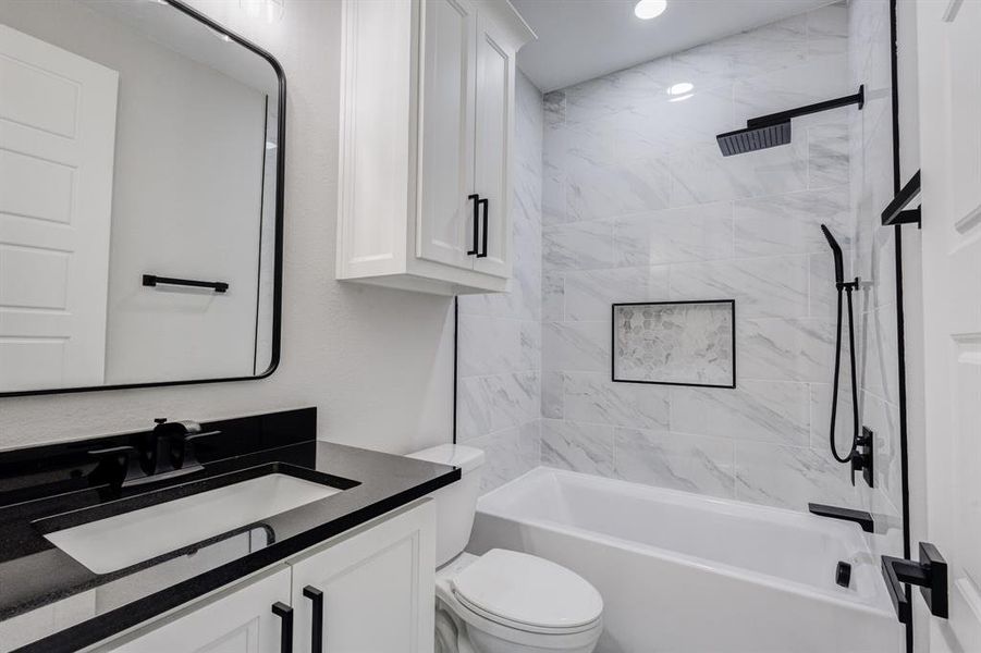 Bathroom featuring a tub/shower combination with white marble-look tile surround and a tiled niche