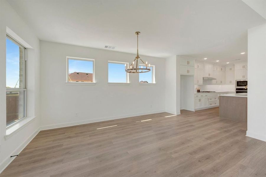 Open-concept living area featuring wood-finish flooring, a modern chandelier, and multiple windows