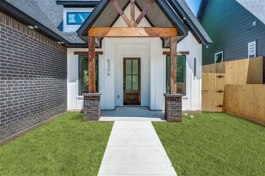 Modern farmhouse-inspired facade featuring white vertical siding and dark brick accents Modern farmhouse-inspired facade featuring white vertical siding and dark brick accents