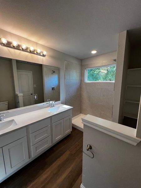 Bathroom featuring vanity, toilet, hardwood / wood-style floors, and tiled shower