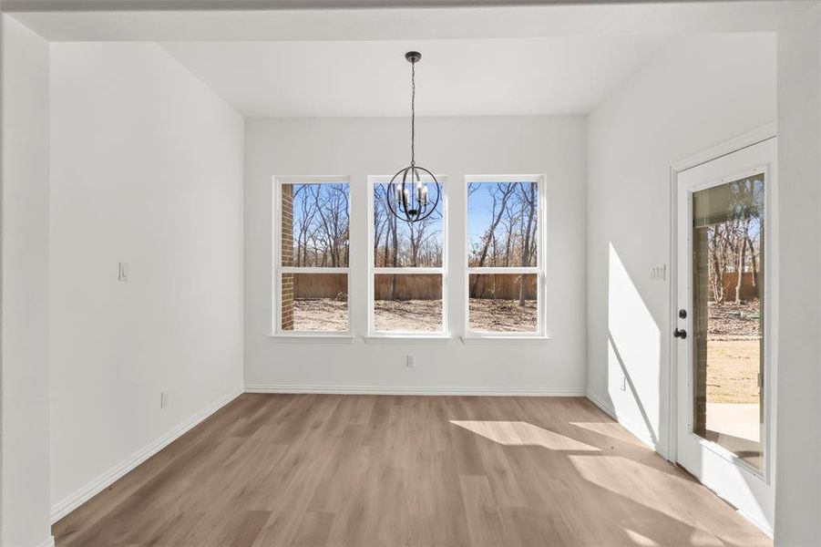 Unfurnished dining area featuring light wood-type flooring and an inviting chandelier