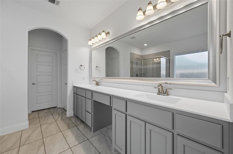Bathroom with a shower stall, double vanity, and light tile patterned floors