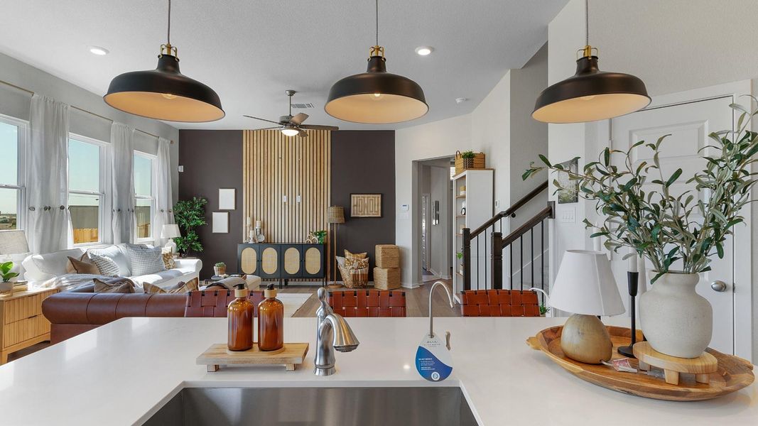 An open-concept living area boasts a sleek kitchen island, ample natural light, and a stylish dark accent wall. An open-concept living area boasts a sleek kitchen island, ample natural light, and a stylish dark accent wall.