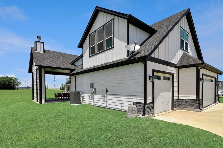 Rear view of house with a shingled roof, board and batten siding, and a yard Rear view of house with a shingled roof, board and batten siding, and a yard