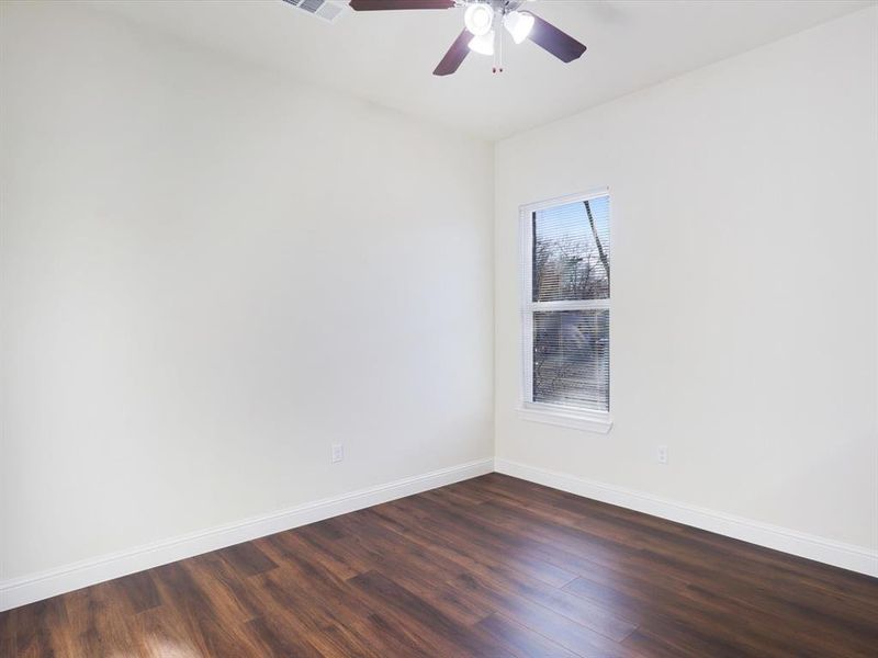 Empty room with dark wood-type flooring and ceiling fan Empty room with dark wood-type flooring and ceiling fan