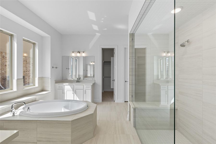 Bathroom with a stall shower, vanity, a bath, a spacious closet, and light tile patterned flooring
