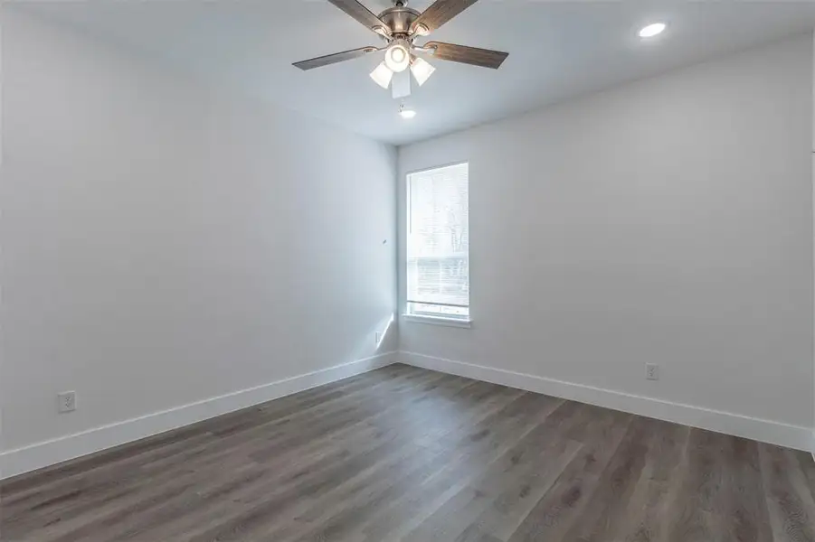 Spare room with ceiling fan and dark wood-type flooring