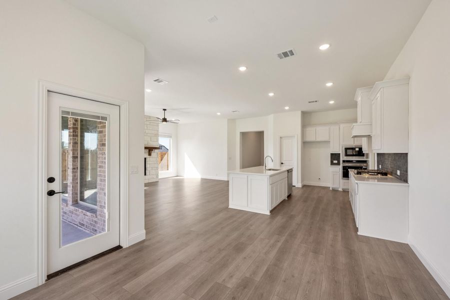 Open-concept kitchen and living area with white cabinets, center island, and wood-look floors Open-concept kitchen and living area with white cabinets, center island, and wood-look floors