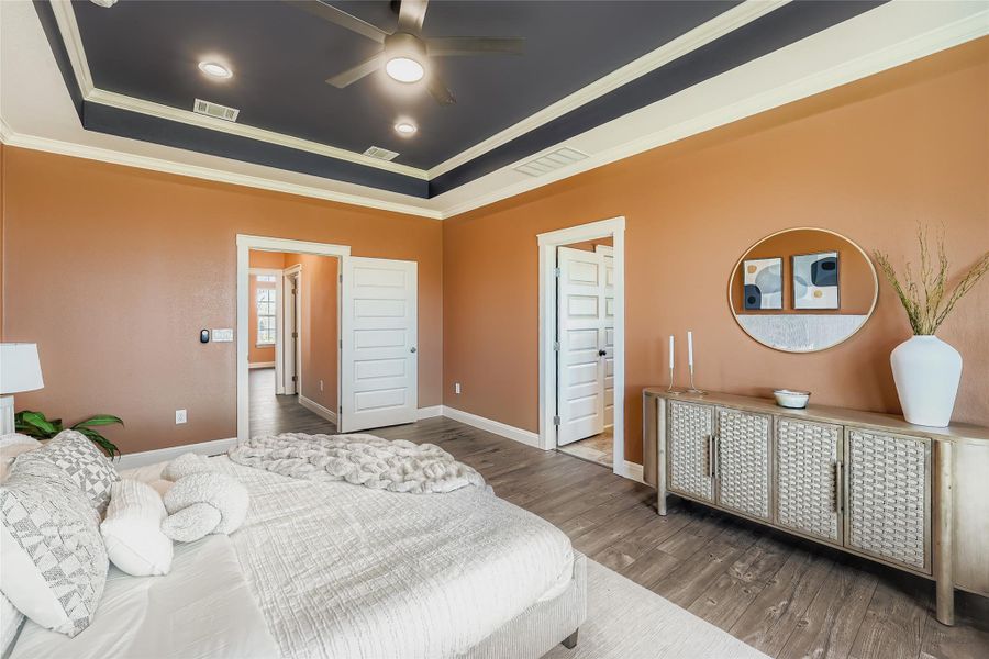 Bedroom featuring wood finished floors, crown molding, a tray ceiling, and a ceiling fan