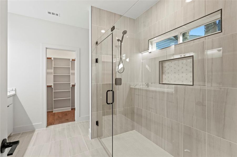 Full bathroom featuring a walk in closet, visible vents, a shower stall, vanity, and baseboards