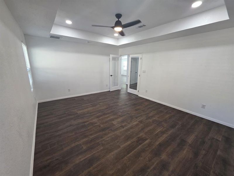 Spare room featuring a raised ceiling, dark wood-style floors, recessed lighting, and a ceiling fan Spare room featuring a raised ceiling, dark wood-style floors, recessed lighting, and a ceiling fan