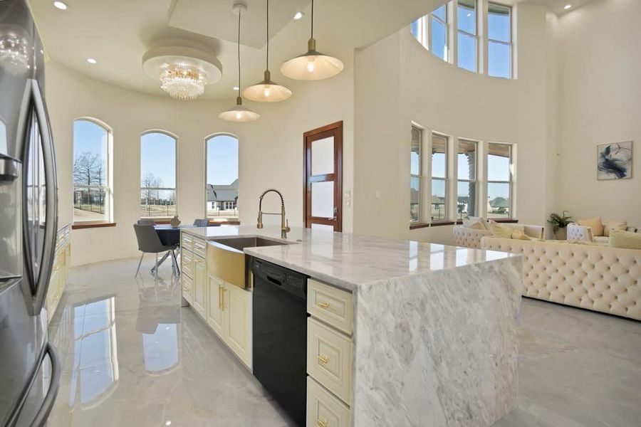 Kitchen with stainless steel refrigerator with ice dispenser, sink, decorative light fixtures, dishwasher, and light stone countertops