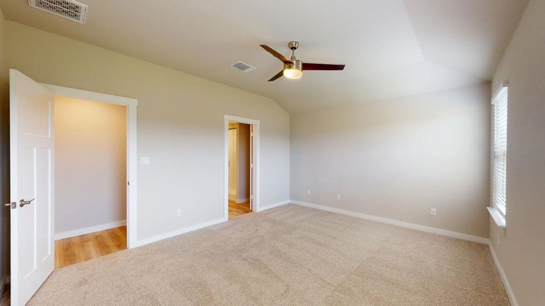 Unfurnished bedroom featuring light colored carpet, a ceiling fan, and vaulted ceiling