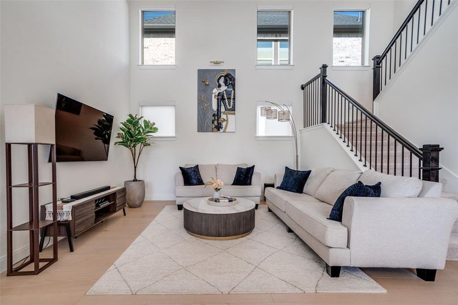 Living area featuring a high ceiling, plenty of natural light, and light wood-style floors