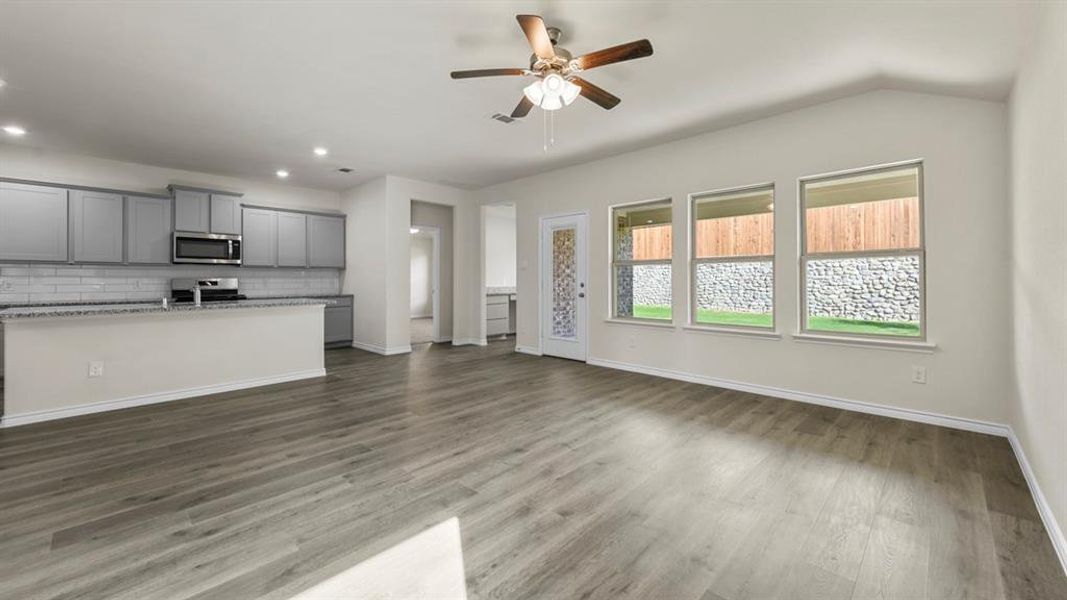 Open-concept living space with wood-finish flooring, vaulted ceilings, and a ceiling fan