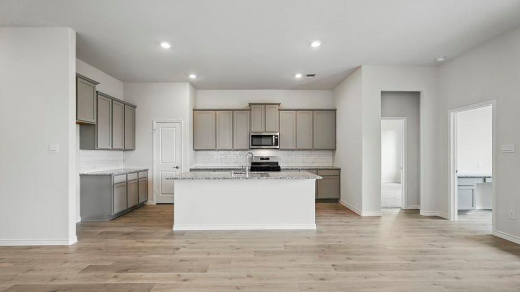 Kitchen featuring gray cabinetry, light stone countertops, an island with sink, stainless steel appliances, and recessed lighting