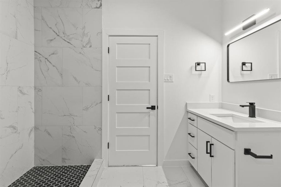 Primary bath with marble finish floor, baseboards, vanity, and a marble finish shower