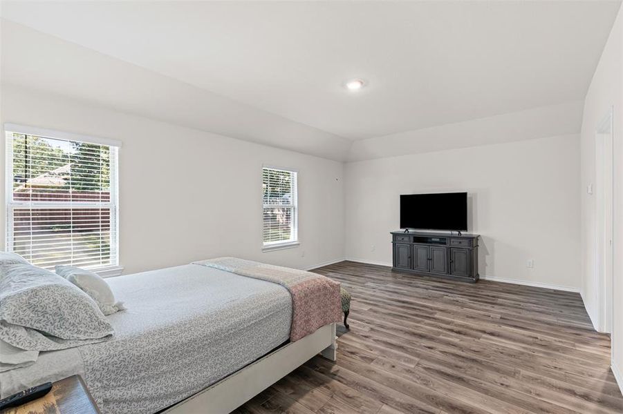 Expansive primary suite with oversized windows, natural light, and luxury vinyl plank flooring. Expansive primary suite with oversized windows, natural light, and luxury vinyl plank flooring.
