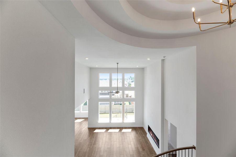 Hallway featuring a chandelier, wood finished floors, a high ceiling, and recessed lighting Hallway featuring a chandelier, wood finished floors, a high ceiling, and recessed lighting