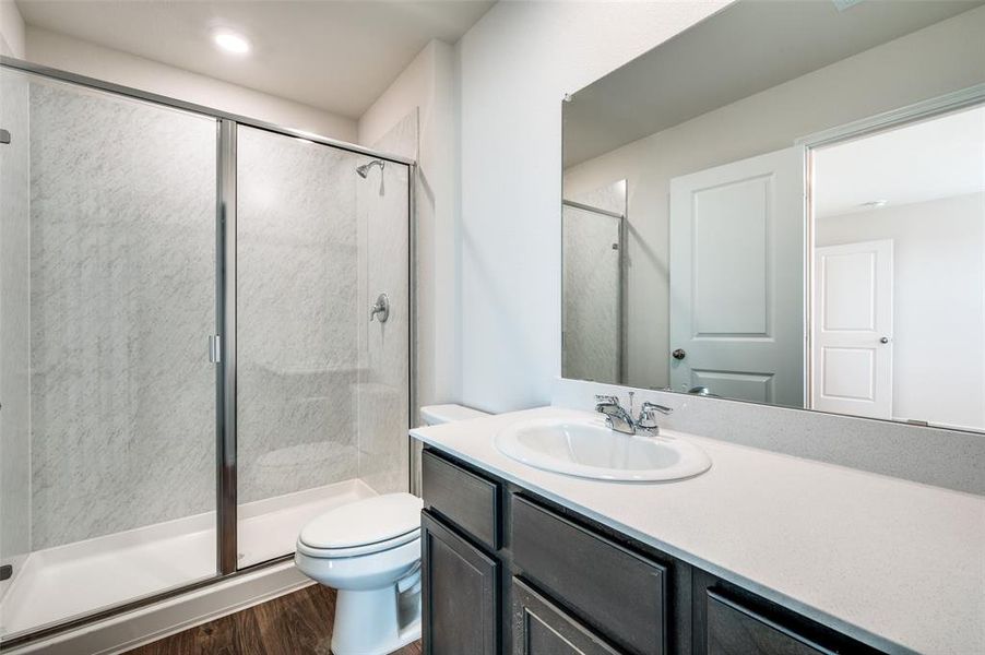 Bathroom featuring hardwood / wood-style floors, vanity, toilet, and walk in shower