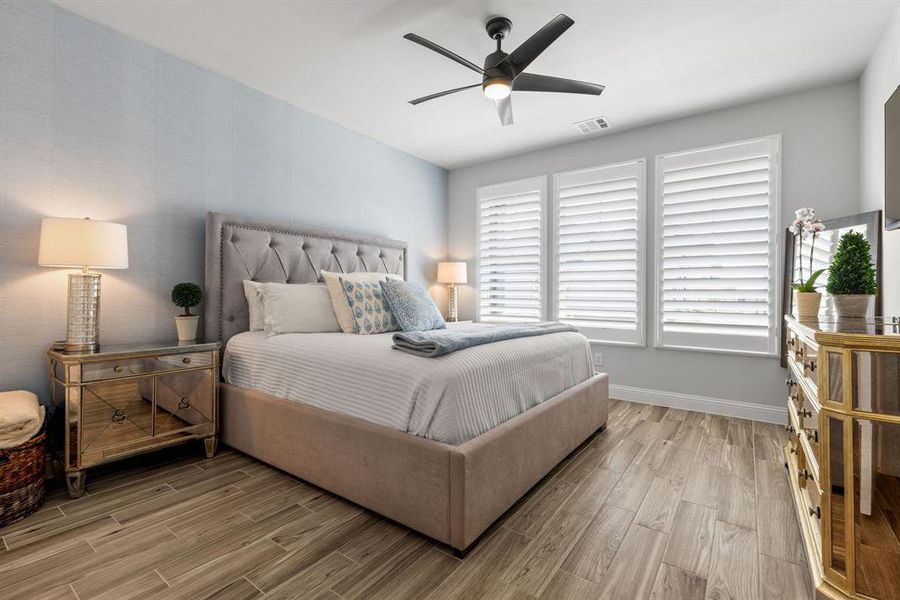 The primary bedroom features a designer accent wall with elegant wallpaper, creating a stylish focal point that adds warmth and character to the space.