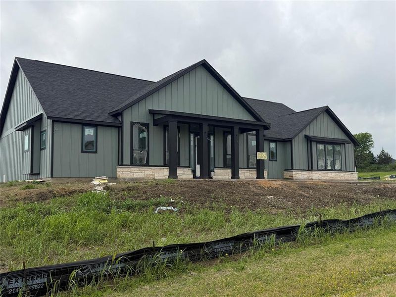 View of front of property featuring a shingled roof, board and batten siding, covered porch, and stone siding View of front of property featuring a shingled roof, board and batten siding, covered porch, and stone siding