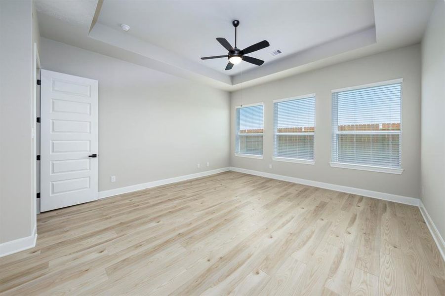 The spacious primary bedroom has beautiful ceilings and hardwood flooring.