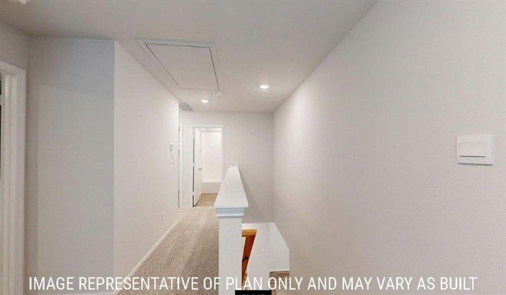 Hallway featuring light-toned carpeting, white walls, recessed ceiling lighting, and a white handrail Hallway featuring light-toned carpeting, white walls, recessed ceiling lighting, and a white handrail