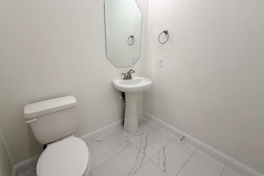 Bathroom featuring baseboards and light marble finish floors