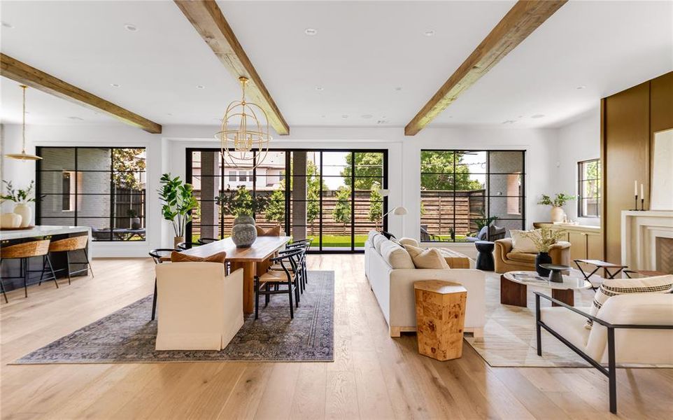 Living room with light wood-type flooring, a chandelier, and beamed ceiling