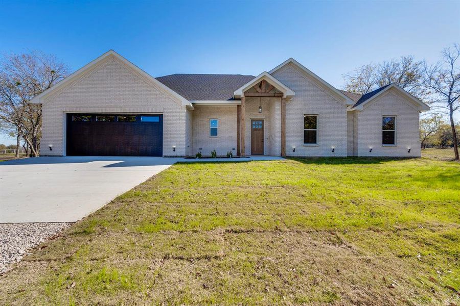 View of front of property featuring a front lawn and a garage