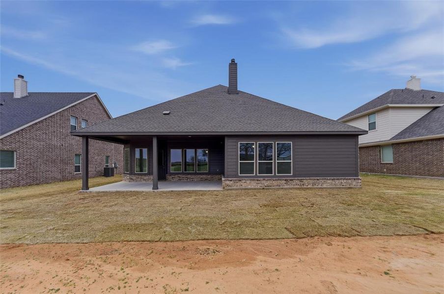 Back of house with a patio area, a yard, a shingled roof, and a chimney