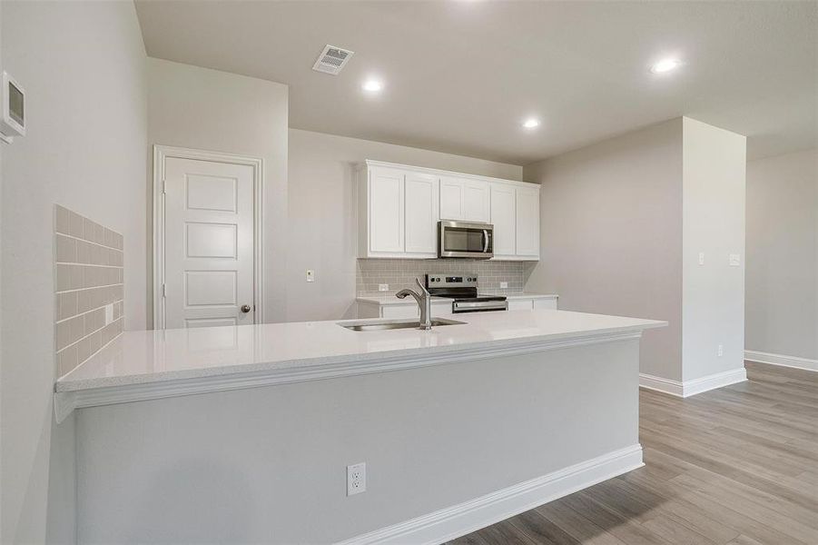 Kitchen featuring light countertops, appliances with stainless steel finishes, backsplash, white cabinets, and recessed lighting Kitchen featuring light countertops, appliances with stainless steel finishes, backsplash, white cabinets, and recessed lighting