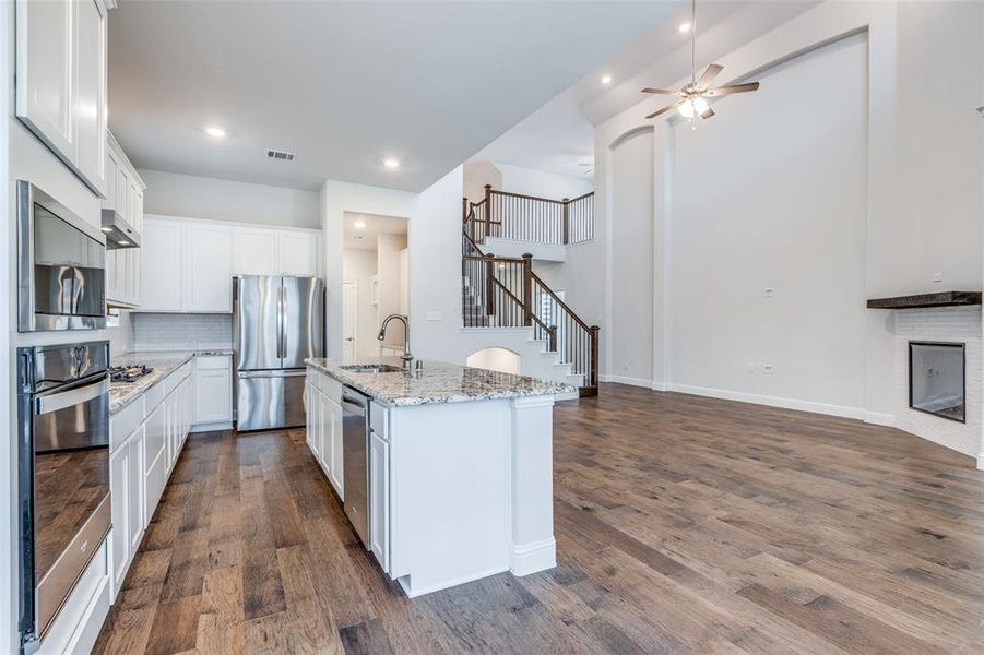Kitchen featuring appliances with stainless steel finishes, a sink, ceiling fan, dark wood-type flooring, and tasteful backsplash