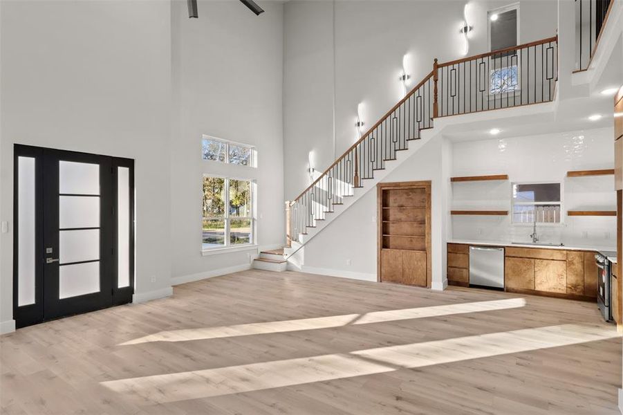 Entrance foyer with light wood-type flooring, a towering ceiling, and sink