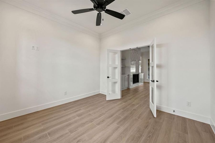 Unfurnished room with ornamental molding, light wood-style flooring, and a ceiling fan Unfurnished room with ornamental molding, light wood-style flooring, and a ceiling fan