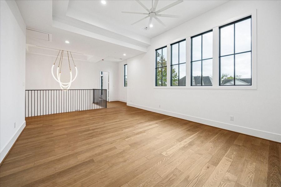 Light flows across the upper level where a dramatic chandelier adds architectural presence. Black metal railing keeps lines clean while the wide hall connects the upstairs bedrooms and game room with an elevated sense of openness. Light flows across the upper level where a dramatic chandelier adds architectural presence. Black metal railing keeps lines clean while the wide hall connects the upstairs bedrooms and game room with an elevated sense of openness.