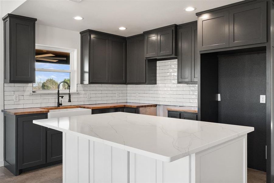 Kitchen with a kitchen island, decorative backsplash, recessed lighting, dual tone cabinetry, and butcher block counters