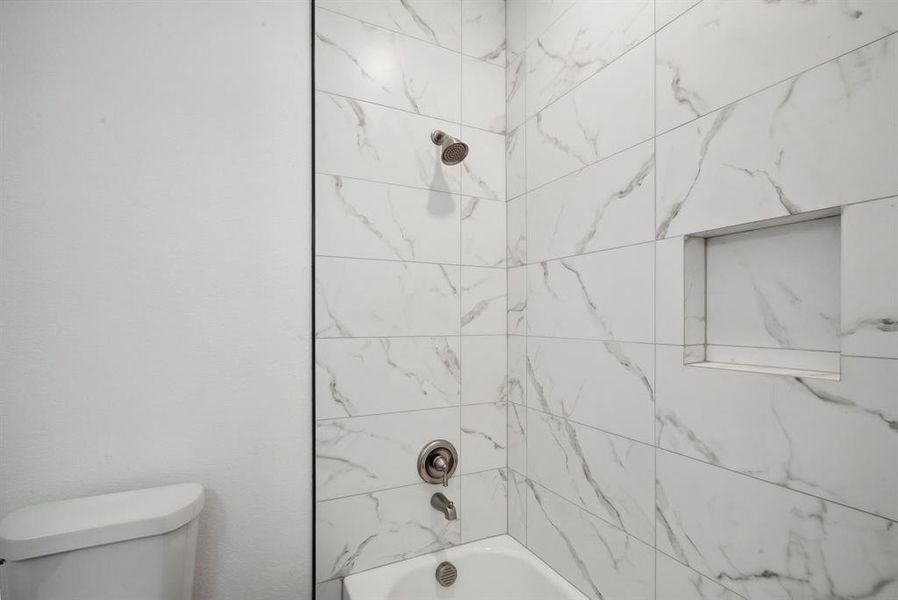 Bathroom with tiled shower / bath combo and toilet