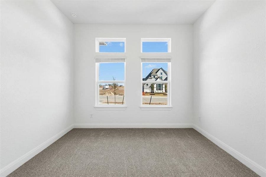 Room featuring two vertical window sets with transom windows, white trim, and a gray carpeted floor